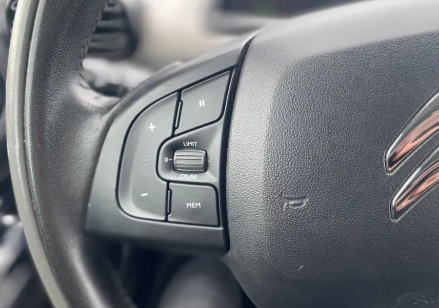 Gros plan sur le volant noir de la Citroën C4 Cactus 2015, montrant les commandes du régulateur de vitesse côté gauche.