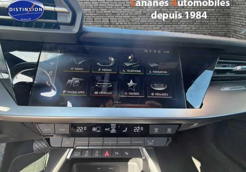 Vue intérieure du tableau de bord de l'Audi A3 Sportback blanc 2023 avec écran tactile et commandes climatisation.