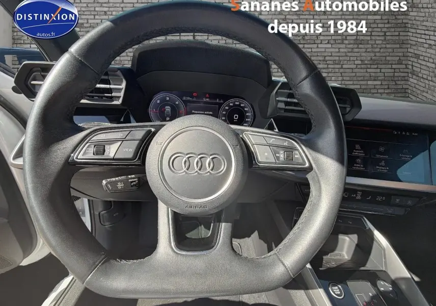 Vue intérieure centrée sur le volant cuir sport multifonctions de l'Audi A3 Sportback blanc 2023.