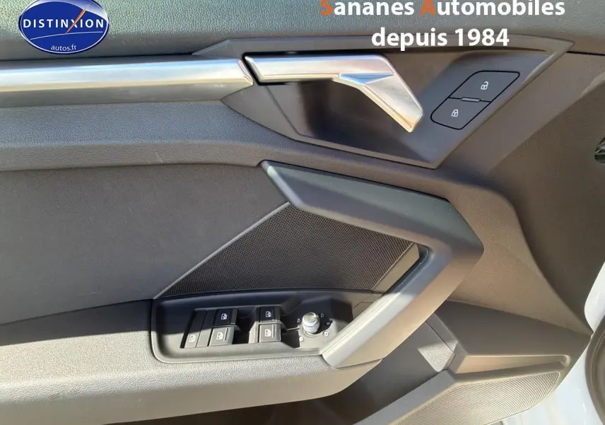 Détail de la porte avant gauche de l'Audi A3 Sportback blanche 2023, montrant les commandes de vitres et la poignée intérieure.