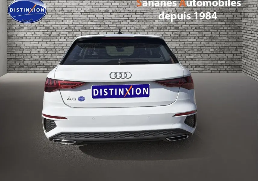 Vue arrière d'une Audi A3 Sportback blanche 2023, avec feux LED et double sortie d'échappement intégrée.