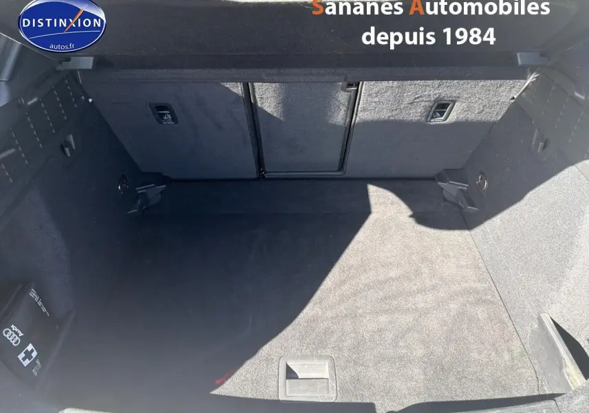 Coffre spacieux et propre d'une Audi A3 Sportback blanche, vue de dessus avec moquette noire et rangements latéraux.