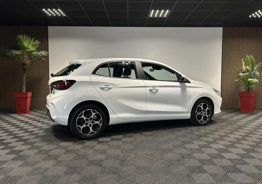 Vue de profil côté gauche d'une MG3 blanche 2025 en hybride, avec jantes alliage et intérieur noir visible.