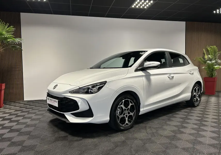 Vue 3/4 avant droite d'une MG3 blanche 2025 avec jantes alliage et calandre noire dans un showroom.