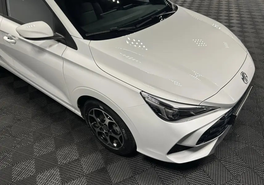 Vue 3/4 avant droit de la MG3 1.5 Hybrid+ blanche avec jantes alliage noires et phares halogènes.