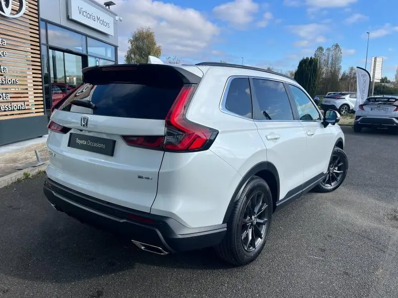 Vue 3/4 arrière droite du Honda CR-V 2024 blanc diamant métallisé avec jantes noires et feux LED distinctifs.
