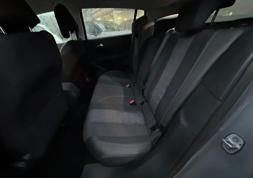 Vue intérieure du siège arrière droit de la Peugeot 308 gris Artense, montrant la banquette en tissu noir avec ceinture de sécurité.