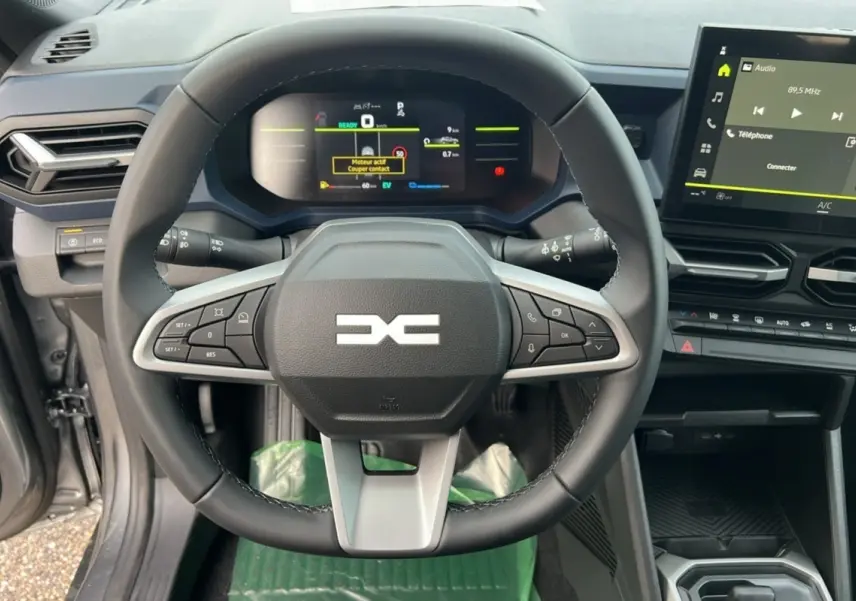 Vue rapprochée du volant multifonctions et du tableau de bord numérique du Dacia Duster HEV 140 noir nacré, version 2025.
