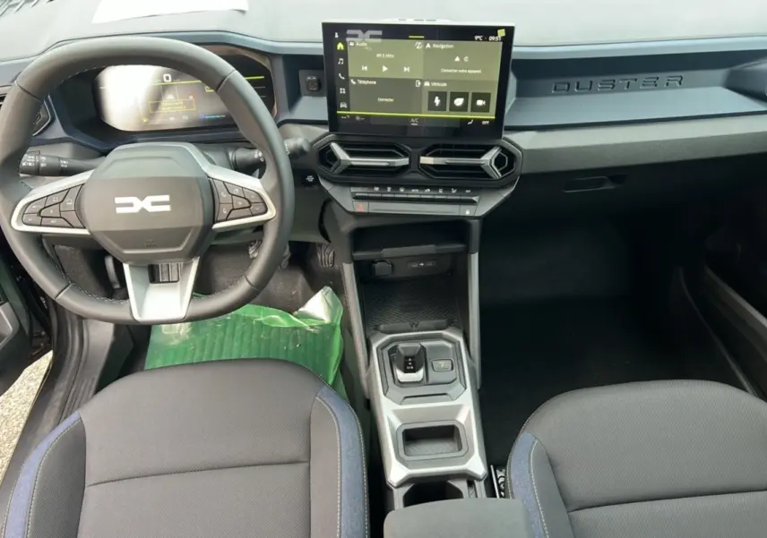 Vue intérieure du tableau de bord et console centrale du Dacia Duster HEV 140 Journey Pack City 2025 avec écran tactile et volant multifonction.