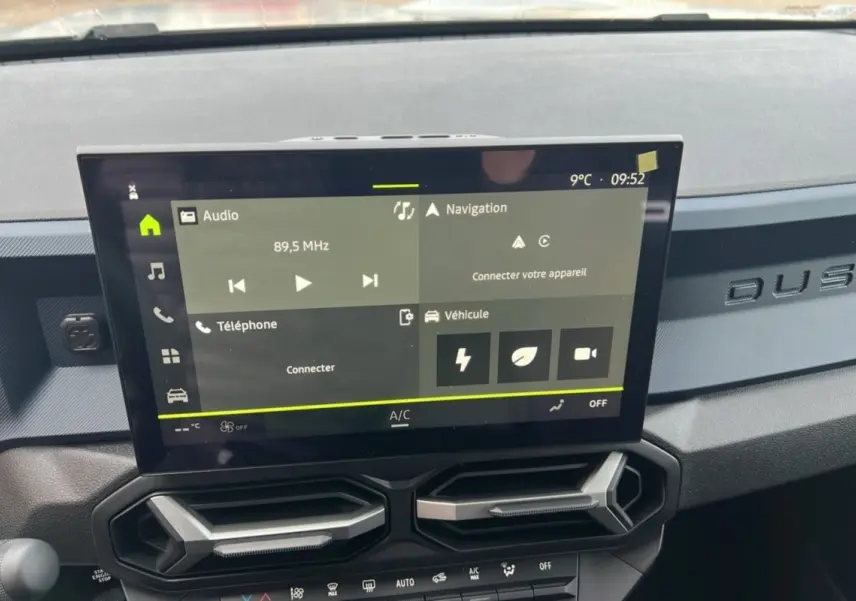 Vue intérieure du tableau de bord du Dacia Duster 2025 avec écran tactile et inscription DUSTER en relief sur la planche.