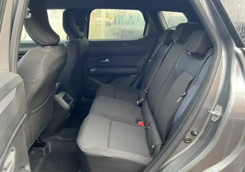 Vue intérieure sur les sièges arrière du Dacia Duster 2025 noir nacré, montrant un habillage tissu gris foncé et bleu.