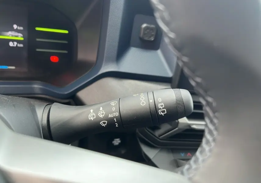 Gros plan sur la commande d'essuie-glace du tableau de bord d'un Dacia Duster 2025 noir nacré HEV 140 Journey Pack City.