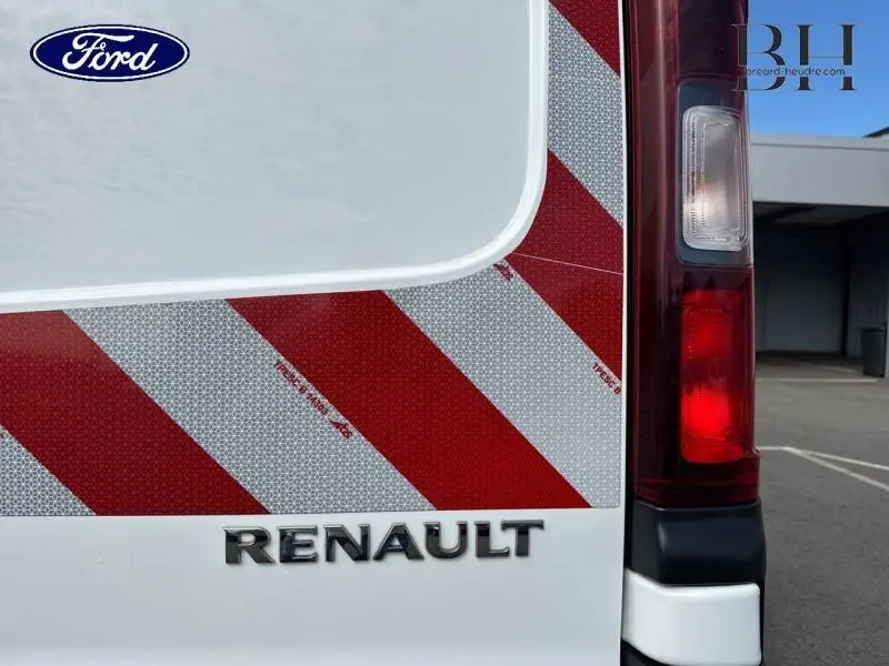 Gros plan sur l'arrière droit blanc glacier du Renault Trafic Fourgon avec marquage réfléchissant rouge et blanc et feu arrière.
