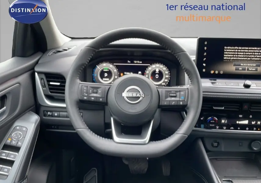Vue intérieure centrée sur le volant du Nissan Qashqai blanc nacré, tableau de bord digital et écran tactile visible.
