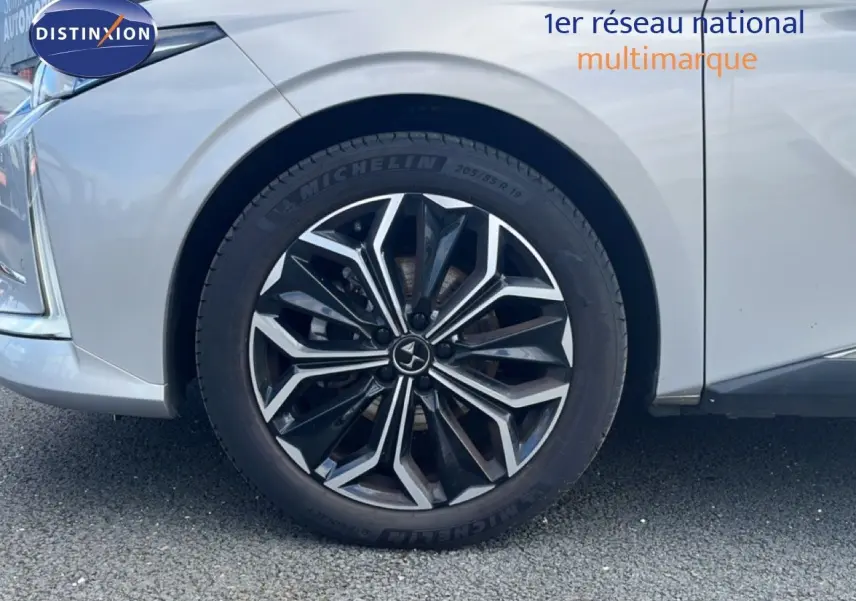 Gros plan sur la roue avant gauche d'une DS4 2024 Cristal Pearl Nacré avec jante alliage noire et argentée.