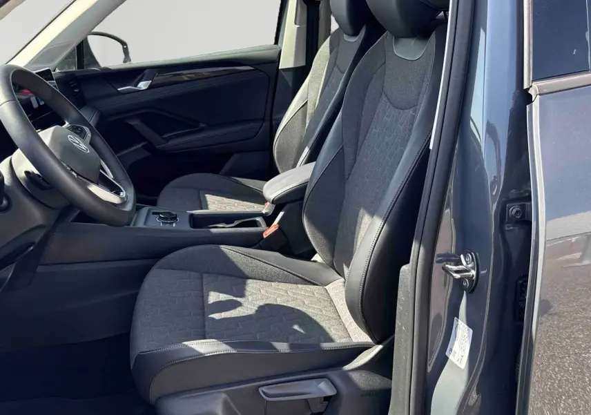 Vue intérieure côté conducteur du Volkswagen Tiguan 2025 gris, avec sièges tissu et cuir et volant multifonction.