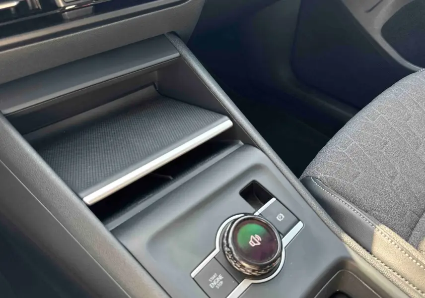 Vue rapprochée de la console centrale grise du Volkswagen Tiguan 2025 avec molette de contrôle et frein à main électrique.