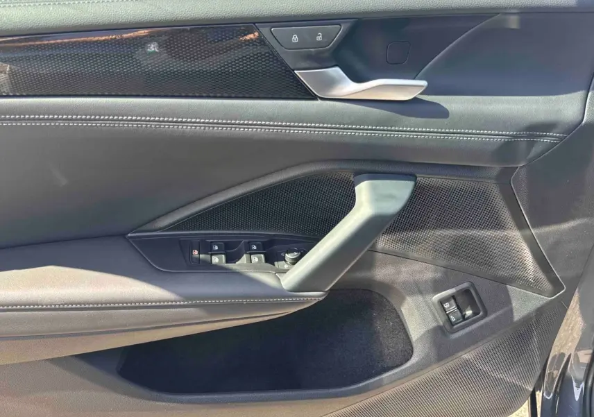 Intérieur côté conducteur du Volkswagen Tiguan 2025 gris, montrant la portière avec commandes électriques et poignée argentée.