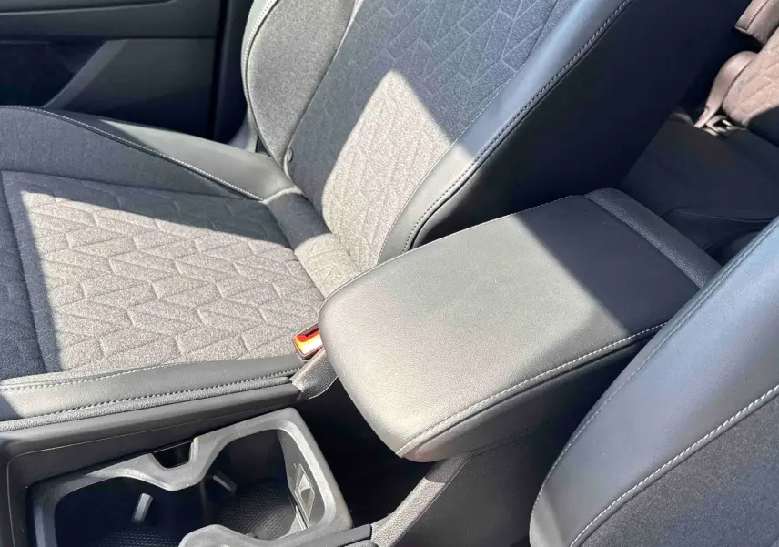 Gros plan sur l'accoudoir central en cuir noir et siège tissu gris du Volkswagen Tiguan 2025, intérieur avant.