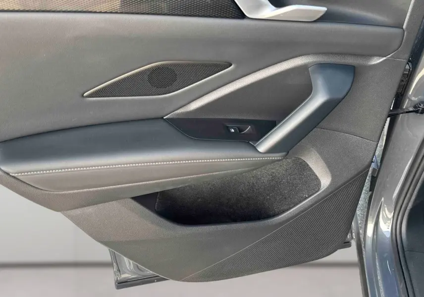 Gros plan sur la porte intérieure côté gauche du Volkswagen Tiguan gris, montrant les commandes et le revêtement en cuir noir.