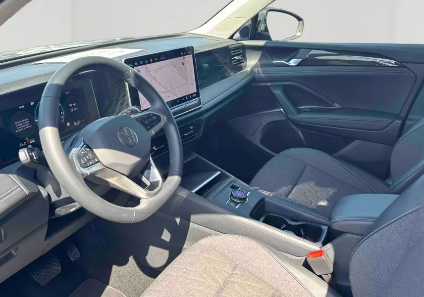 Vue intérieure côté conducteur du Volkswagen Tiguan 2025, tableau de bord moderne avec écran tactile et sièges gris.