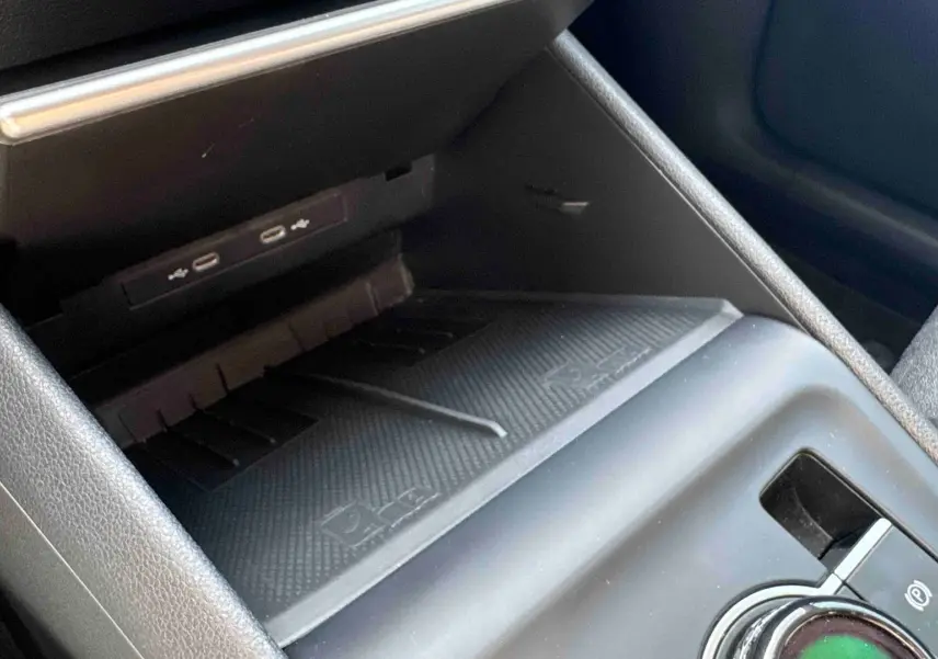 Gros plan sur la console centrale du Volkswagen Tiguan 2025, montrant le chargeur sans fil et le frein de stationnement électrique.