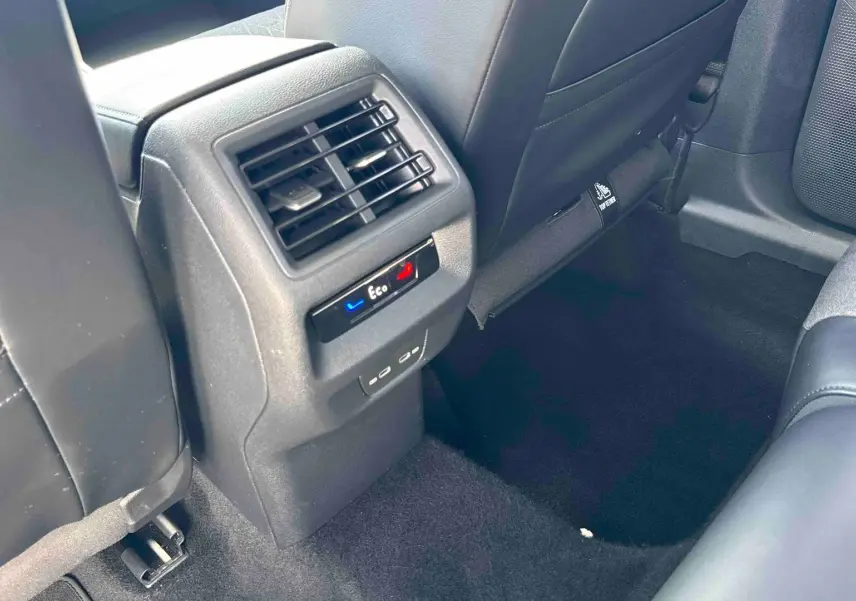 Vue intérieure arrière du Volkswagen Tiguan gris, montrant la console centrale avec bouches d’aération et commandes climatiques Eco.