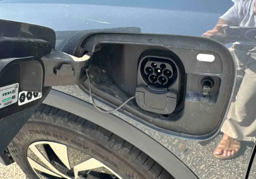 Prise de recharge électrique ouverte côté gauche sur un Volkswagen Tiguan gris, avec jante alliage visible.