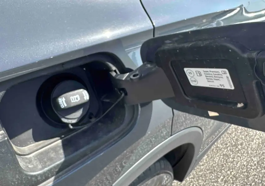 Vue rapprochée de la trappe à carburant côté gauche d’un Volkswagen Tiguan gris 2025 avec bouchon ouvert.