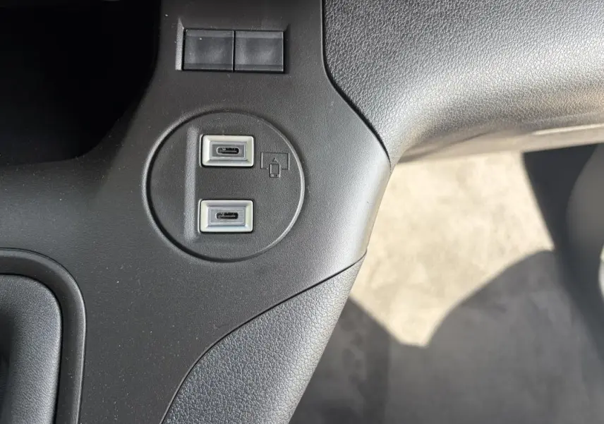 Gros plan sur les deux ports USB-C intégrés dans la console centrale noire du Peugeot Partner blanc.