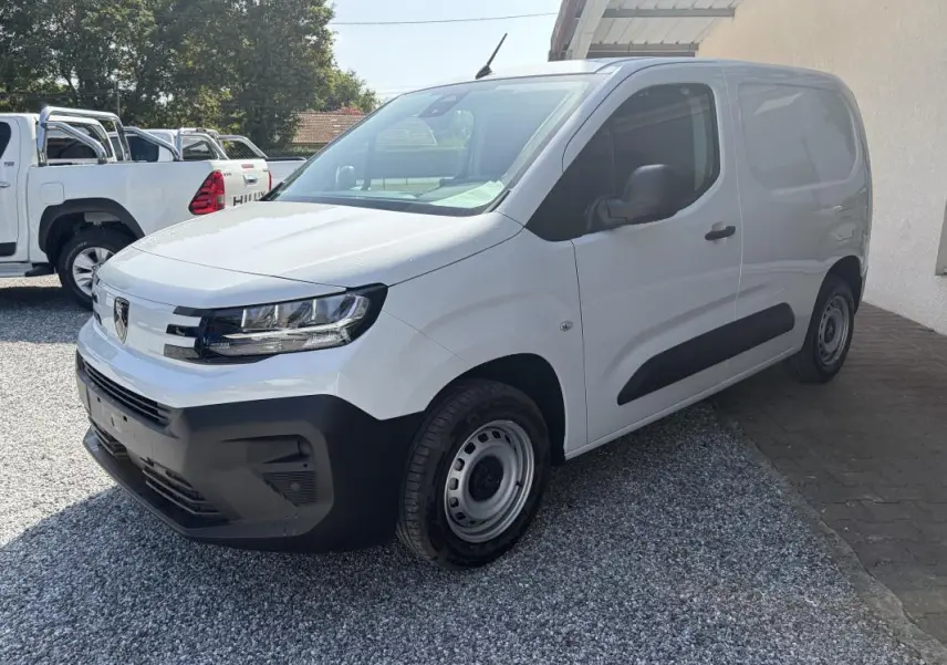 Vue 3/4 avant droit d’un Peugeot Partner blanc 2026, fourgon diesel avec pare-chocs et protections latérales noires.