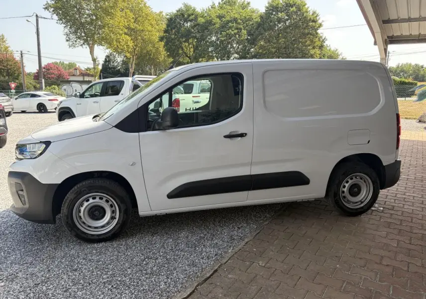 Vue de profil côté gauche d’un Peugeot Partner blanc utilitaire avec porte latérale pleine et jantes acier.