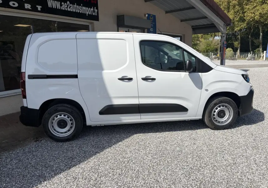 Vue de profil côté droit d’un Peugeot Partner blanc utilitaire avec portes latérales et jantes acier.