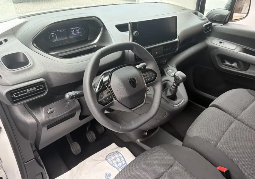 Vue intérieure côté conducteur du Peugeot Partner 2026, montrant le volant multifonctions, levier de vitesse manuel et écran tactile central.