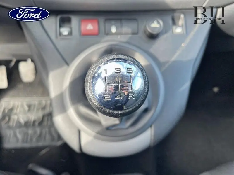 Le levier de vitesses manuel vu de dessus dans un intérieur gris, avec la grille des 5 rapports et la marche arrière visible.