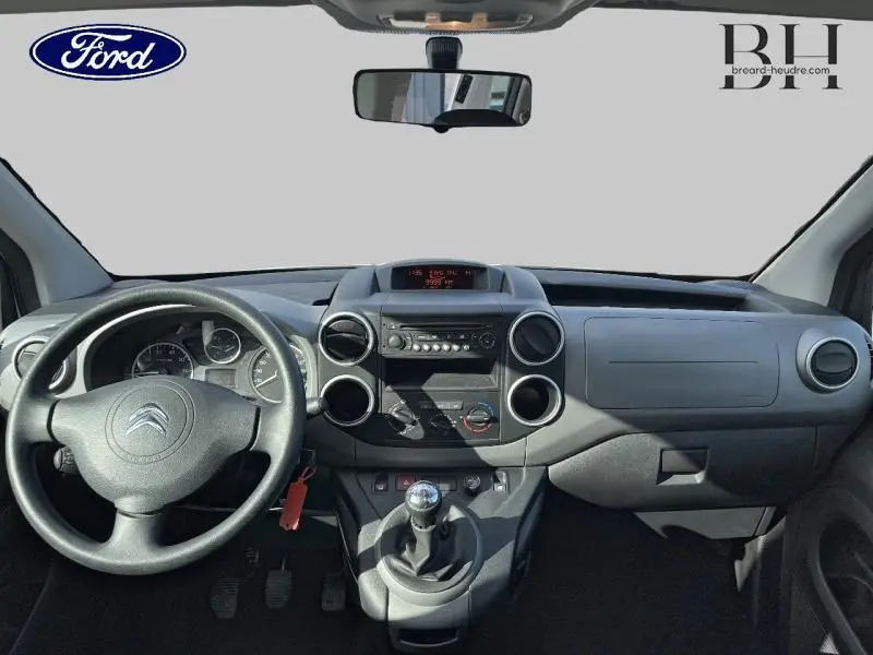 Vue intérieure du tableau de bord et volant noir du Citroën Berlingo Blanc Banquise, avec levier de vitesse manuel central.