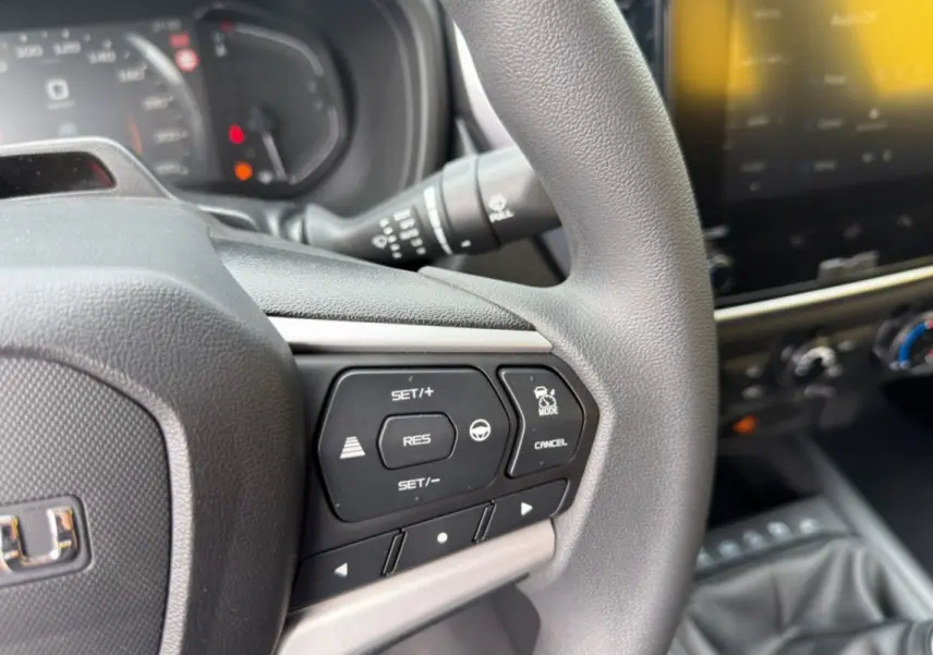 Gros plan sur le volant multifonctions côté gauche de l’Isuzu D-MAX 2026 gris Mercury avec tableau de bord et écran tactile en arrière-plan.