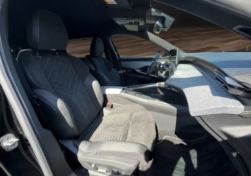 Vue intérieure côté conducteur du Peugeot 5008 2025 noir, mettant en valeur la sellerie Alcantara et le tableau de bord moderne.