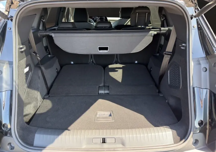 Coffre ouvert d’un Peugeot 5008 noir, vue arrière montrant les sièges rabattus et la tablette cache-bagages.