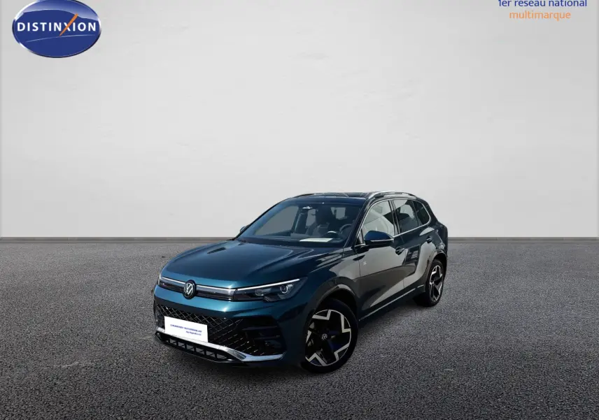 Volkswagen Tiguan 2025 bleu en 3/4 avant droit avec jantes alliage et toit ouvrant panoramique visible.