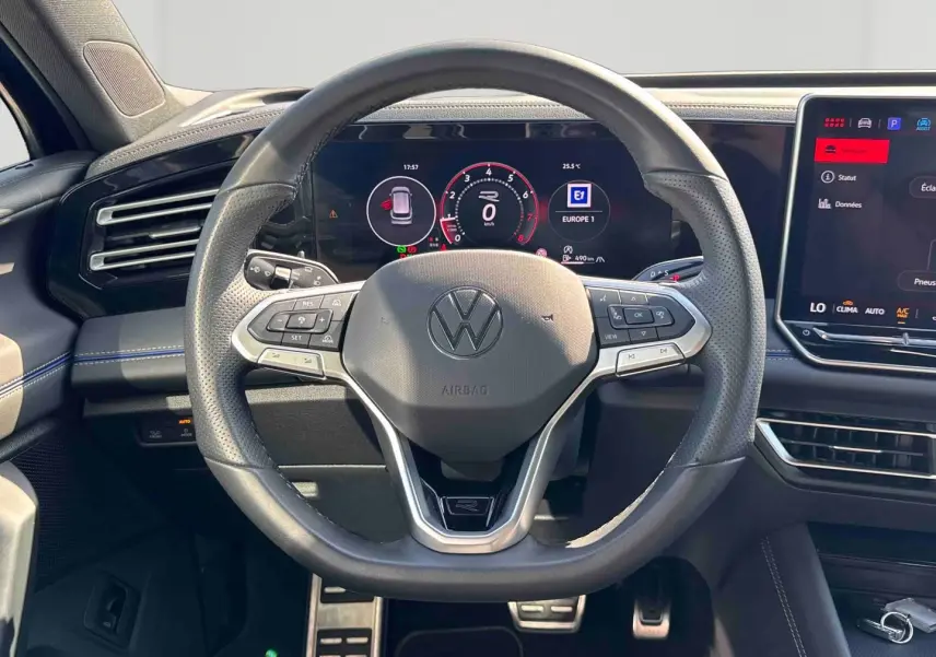 Vue intérieure centrée sur le volant multifonction cuir du Volkswagen Tiguan 2025 avec tableau de bord digital et écran tactile.