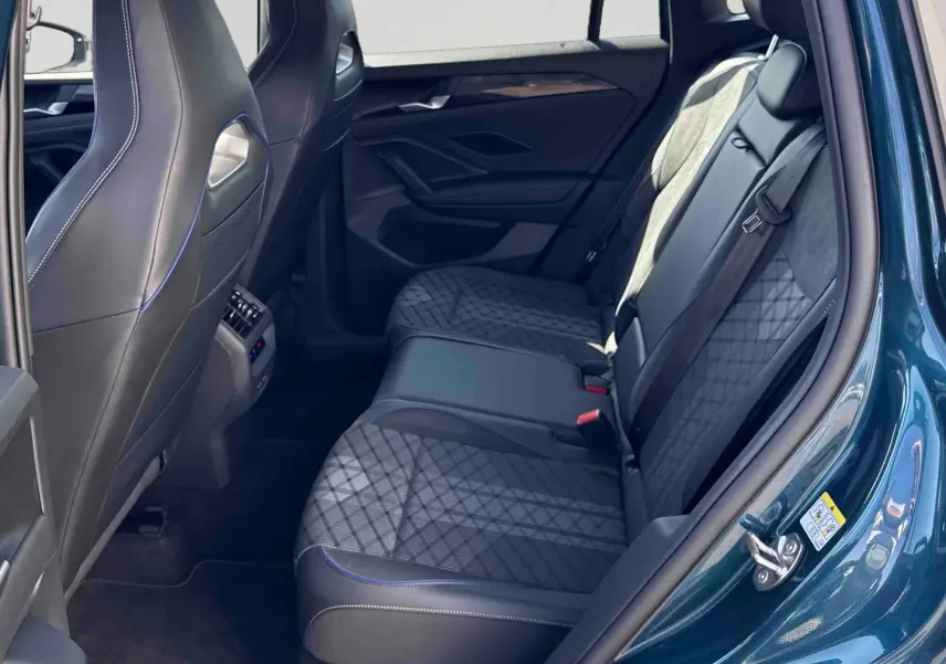 Vue intérieure côté droit sur la banquette arrière du Volkswagen Tiguan 2025 bleu avec sièges en tissu et cuir noir.