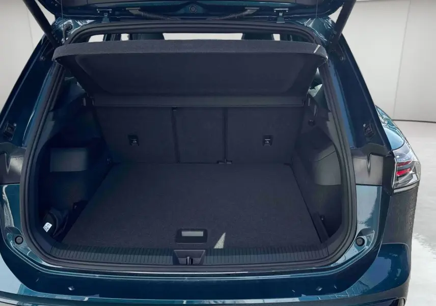 Coffre ouvert vu de l'arrière d'un Volkswagen Tiguan 2025 bleu, montrant l'espace de chargement vide et le hayon relevé.