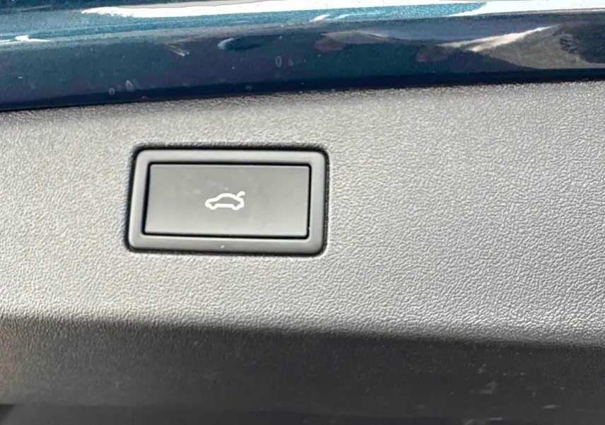 Bouton d'ouverture électrique du hayon sur panneau intérieur bleu du Volkswagen Tiguan 2025.