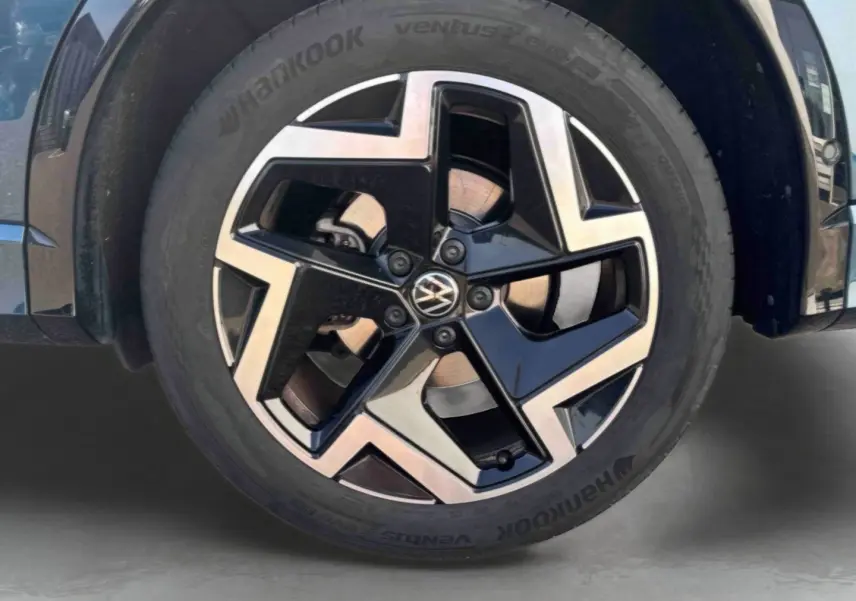 Gros plan sur la jante alliage 19 pouces bicolore du Volkswagen Tiguan bleu, côté avant droit.