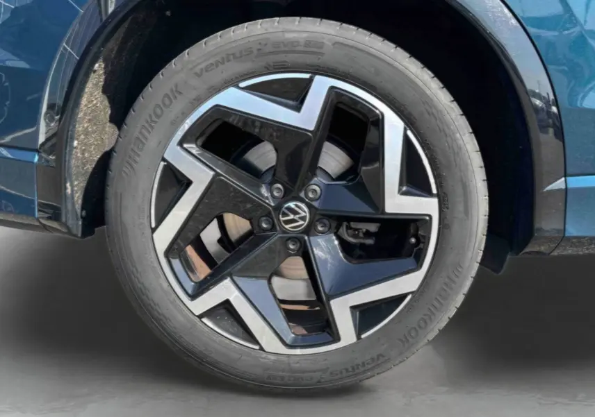 Gros plan sur la jante alliage 19 pouces bicolore du Volkswagen Tiguan bleu, avec pneu Hankook visible.