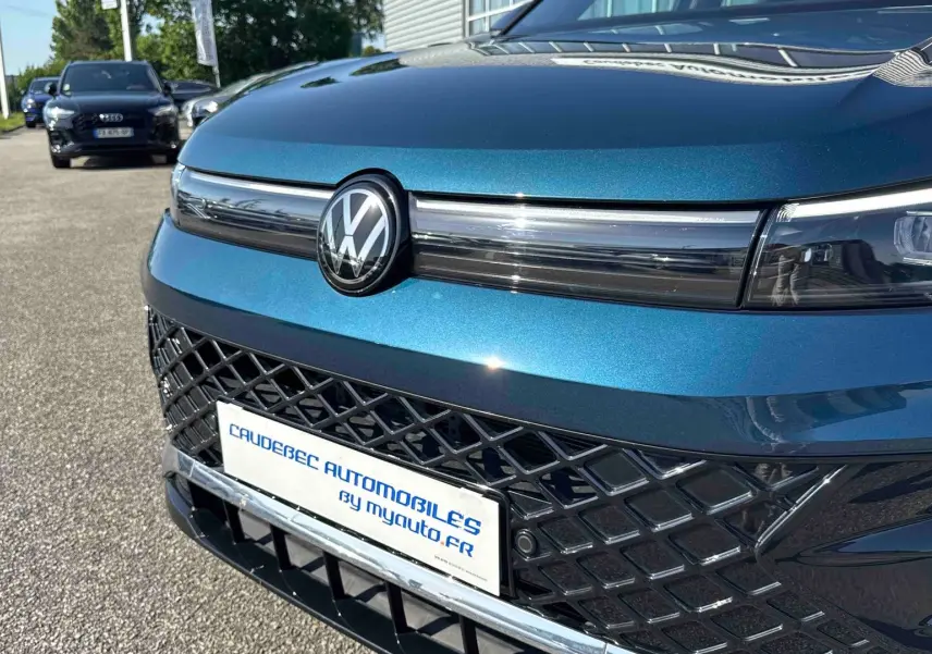 Vue avant rapprochée du Volkswagen Tiguan bleu avec calandre ajourée et logo VW centré brillant.