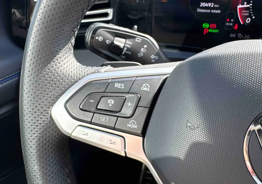 Gros plan sur le volant cuir perforé du Volkswagen Tiguan 2025 avec commandes multifonctions et tableau de bord digital.