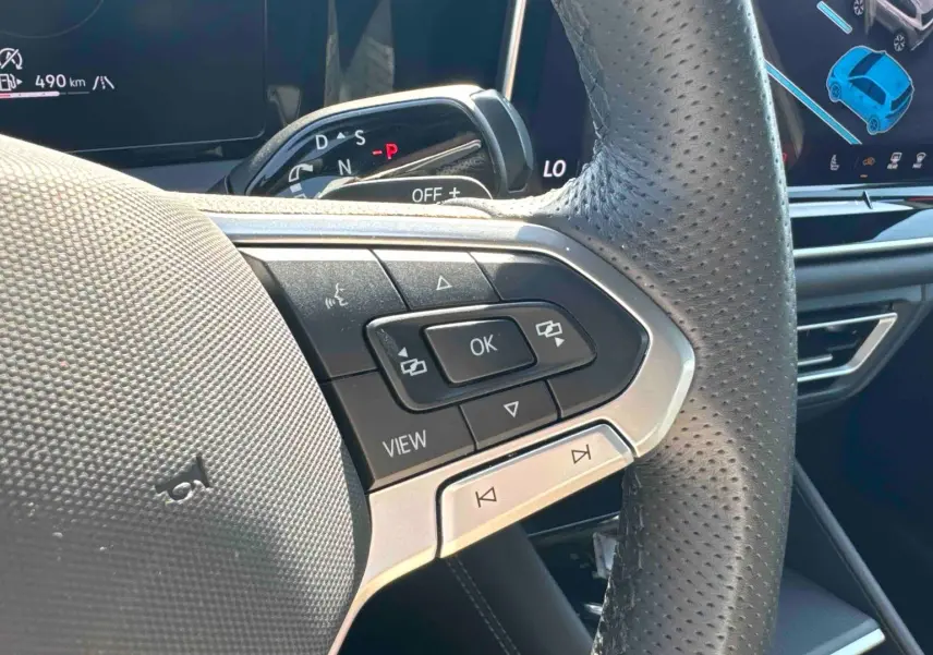 Gros plan sur le volant cuir perforé et les commandes multifonctions du Volkswagen Tiguan 2025, intérieur noir.