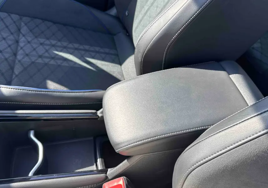 Gros plan sur l'accoudoir central en cuir noir et la console entre les sièges avant du Volkswagen Tiguan.